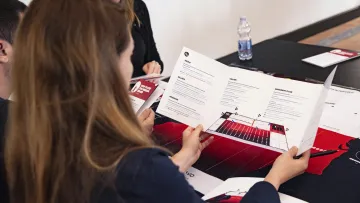 a group of people sitting at a table with papers and pens
